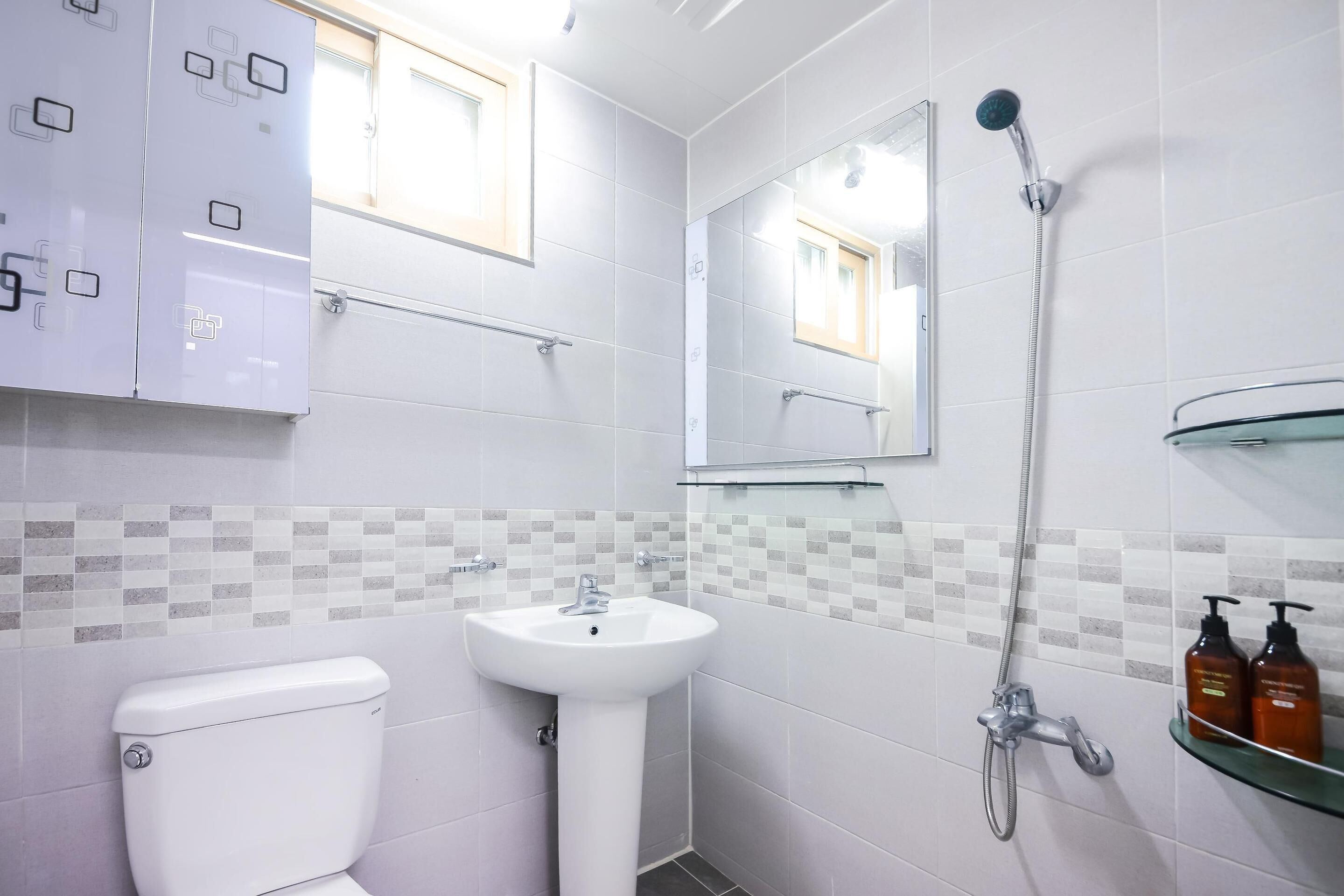 A modern bathroom with a toilet, sink, shower, and a mirror.