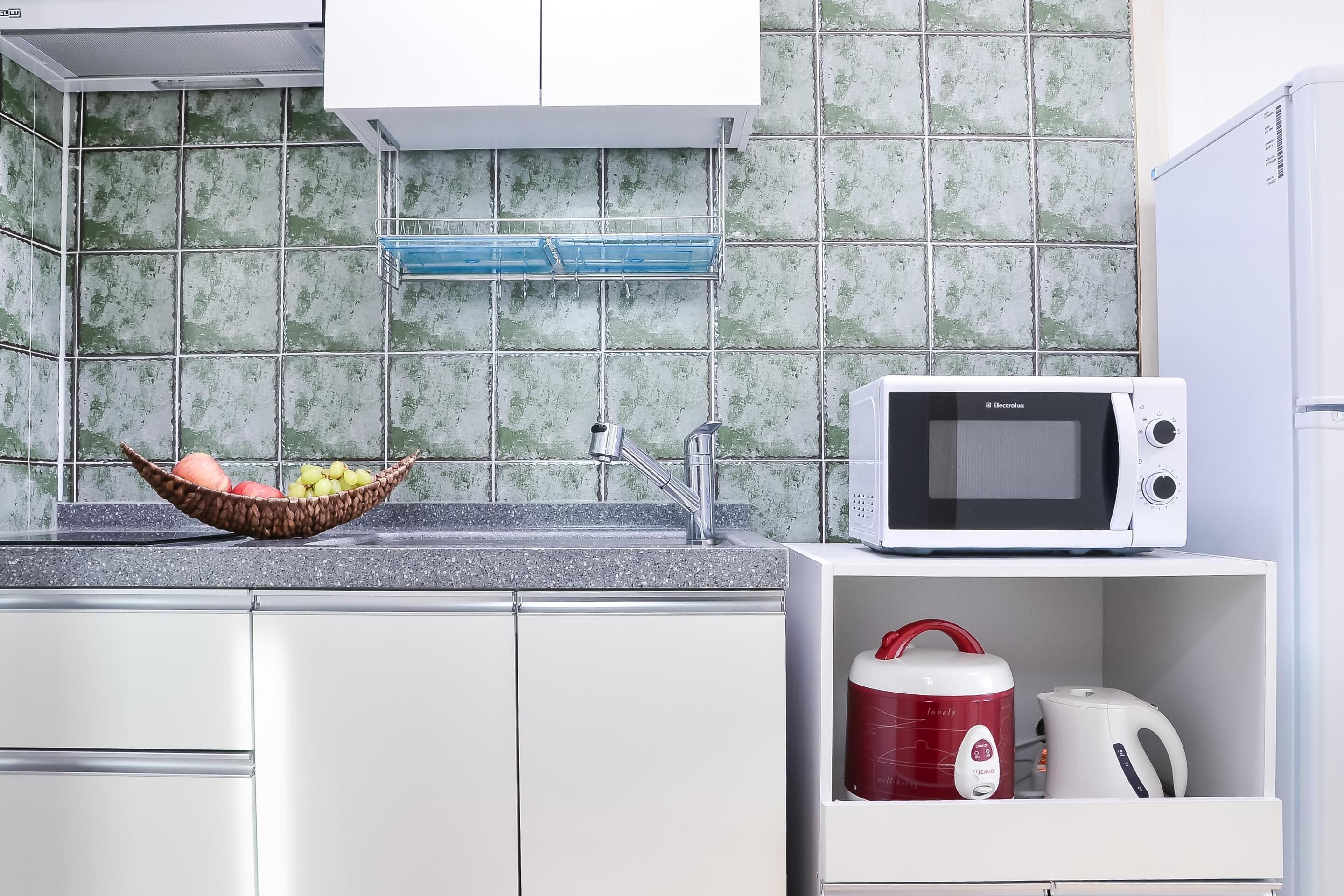 A kitchen with a microwave, a kettle, and a fruit bowl on the counter.