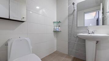 A modern bathroom with a toilet, sink, and glass shower enclosure.