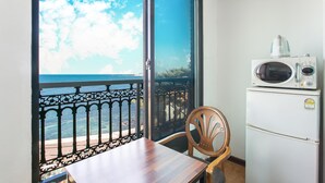 Ein Balkon mit Meerblick, einem Holztisch, einem Stuhl und einem weißen Kühlschrank mit integrierter Mikrowelle.