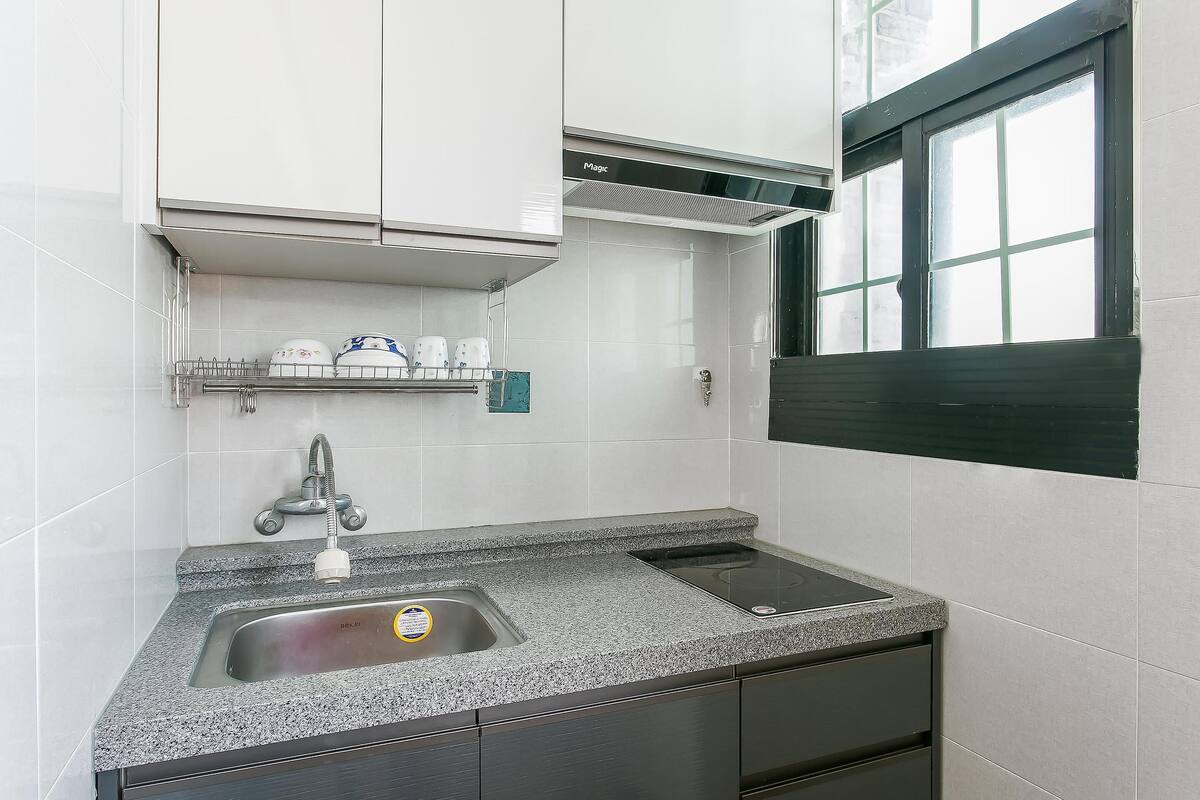 A modern kitchen with a granite countertop, stainless steel sink, and a built-in range hood.