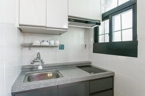 Een moderne keuken met een granieten aanrecht, een roestvrijstalen spoelbak en een inbouwafzuigkap.
