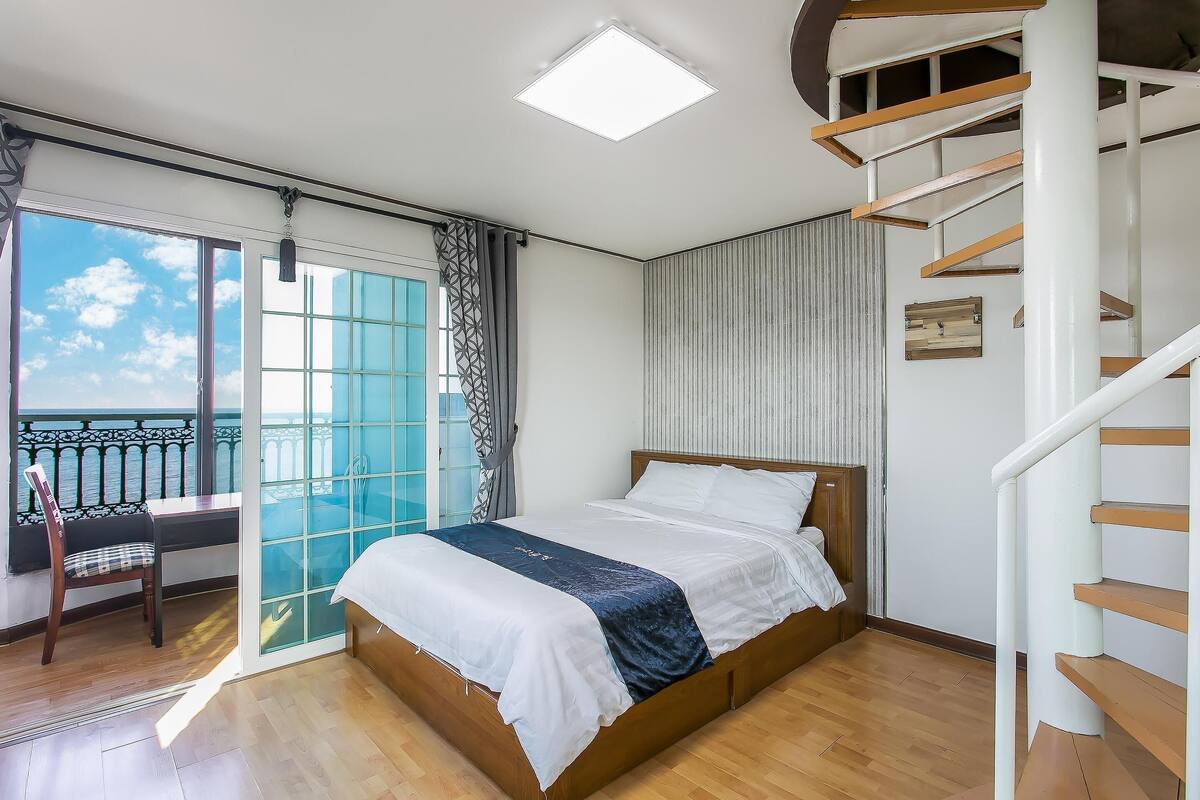 Une chambre à coucher avec un lit, une chaise, une fenêtre et un escalier.