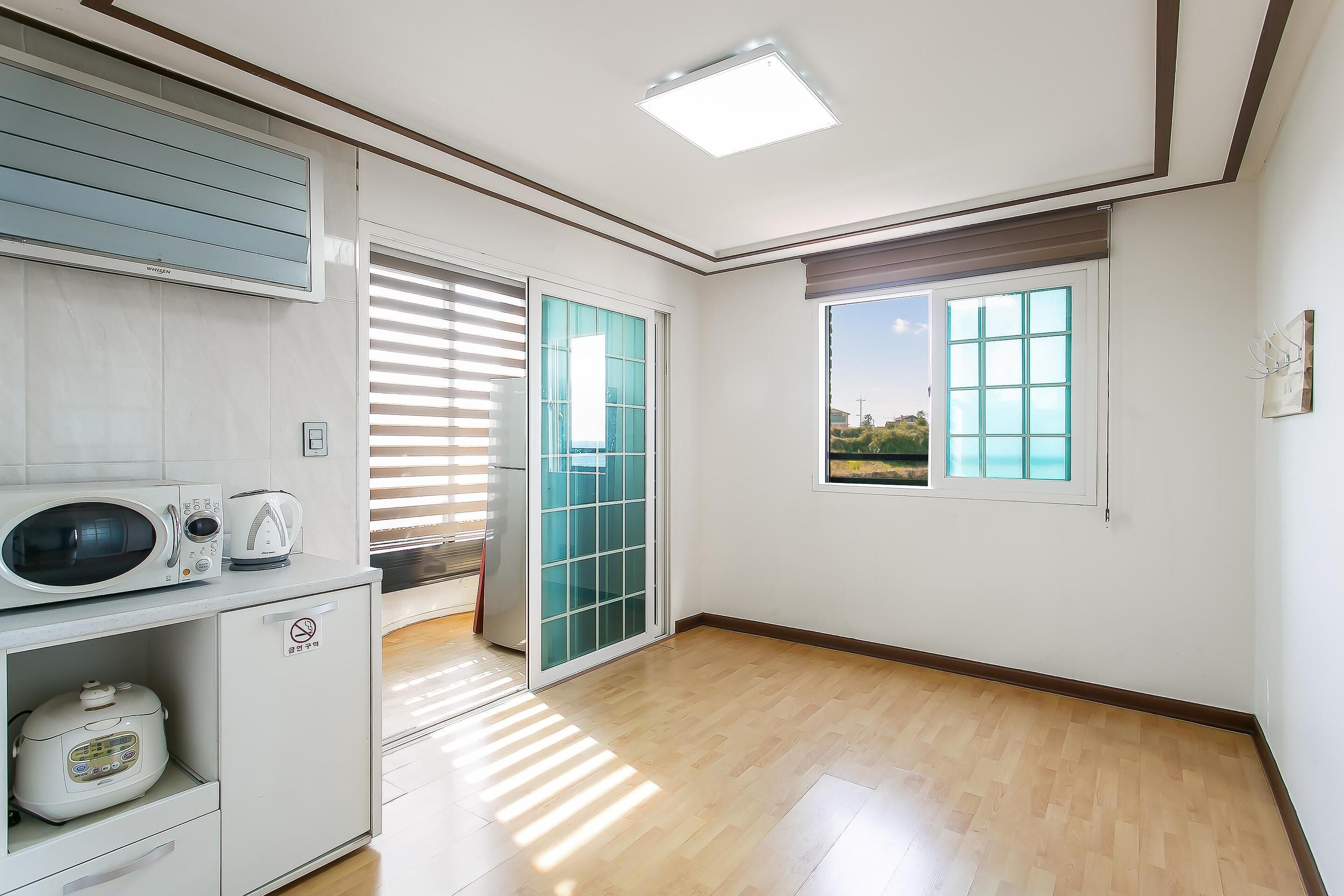 A modern kitchen with a microwave, toaster, and rice cooker on a white countertop.