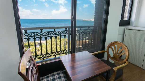 Ein Balkon mit Blick auf das Meer, einem Holztisch und einem Stuhl.