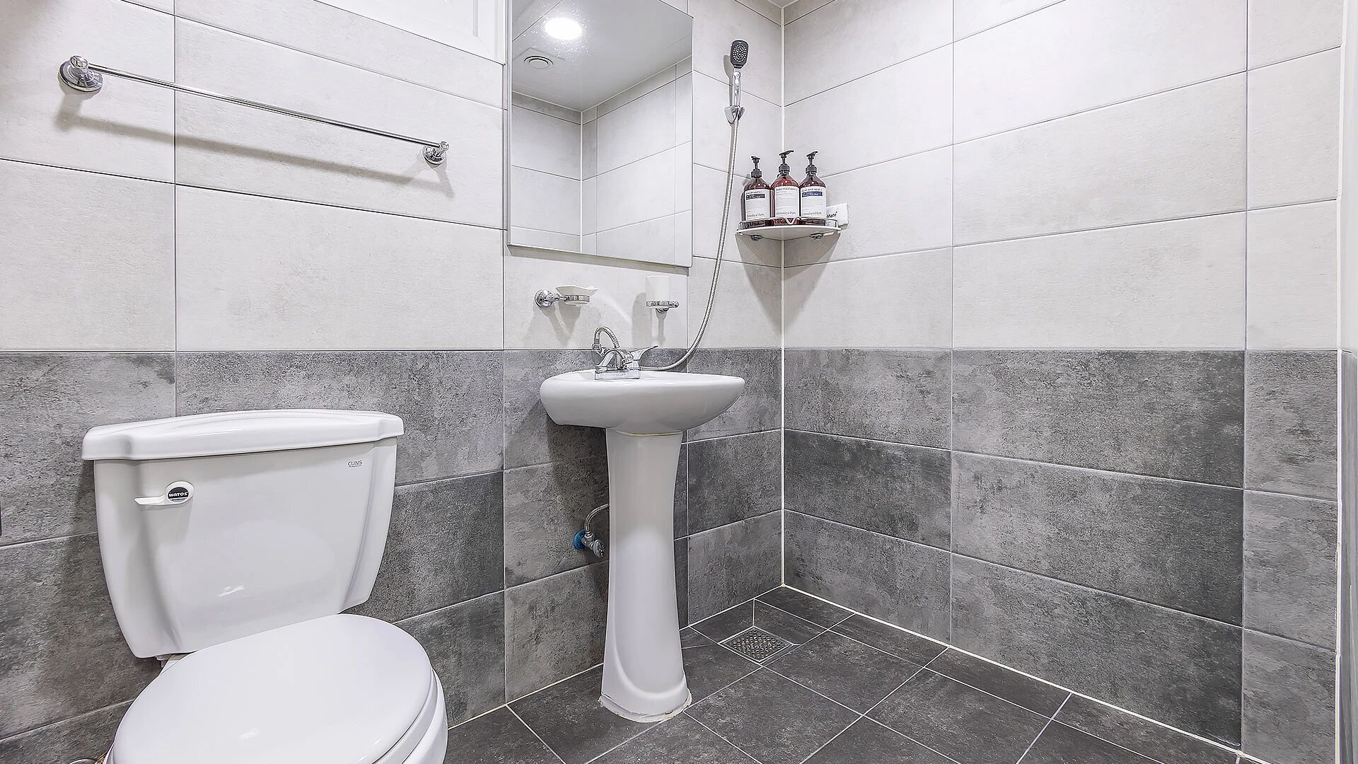 A bathroom with a toilet, a pedestal sink, and a shower.