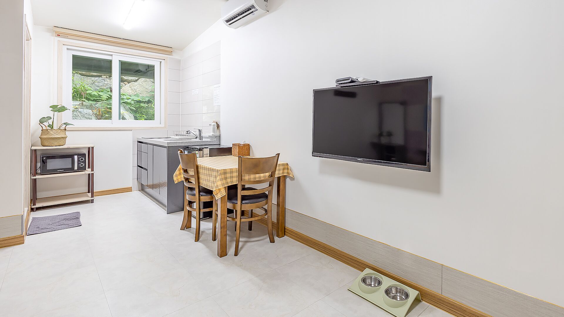Una cocina compacta con comedor, microondas, televisor y ventana con vista a zonas verdes.