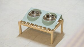 Un distributeur de nourriture pour animaux de compagnie, doté de deux gamelles posées sur un support en bois.