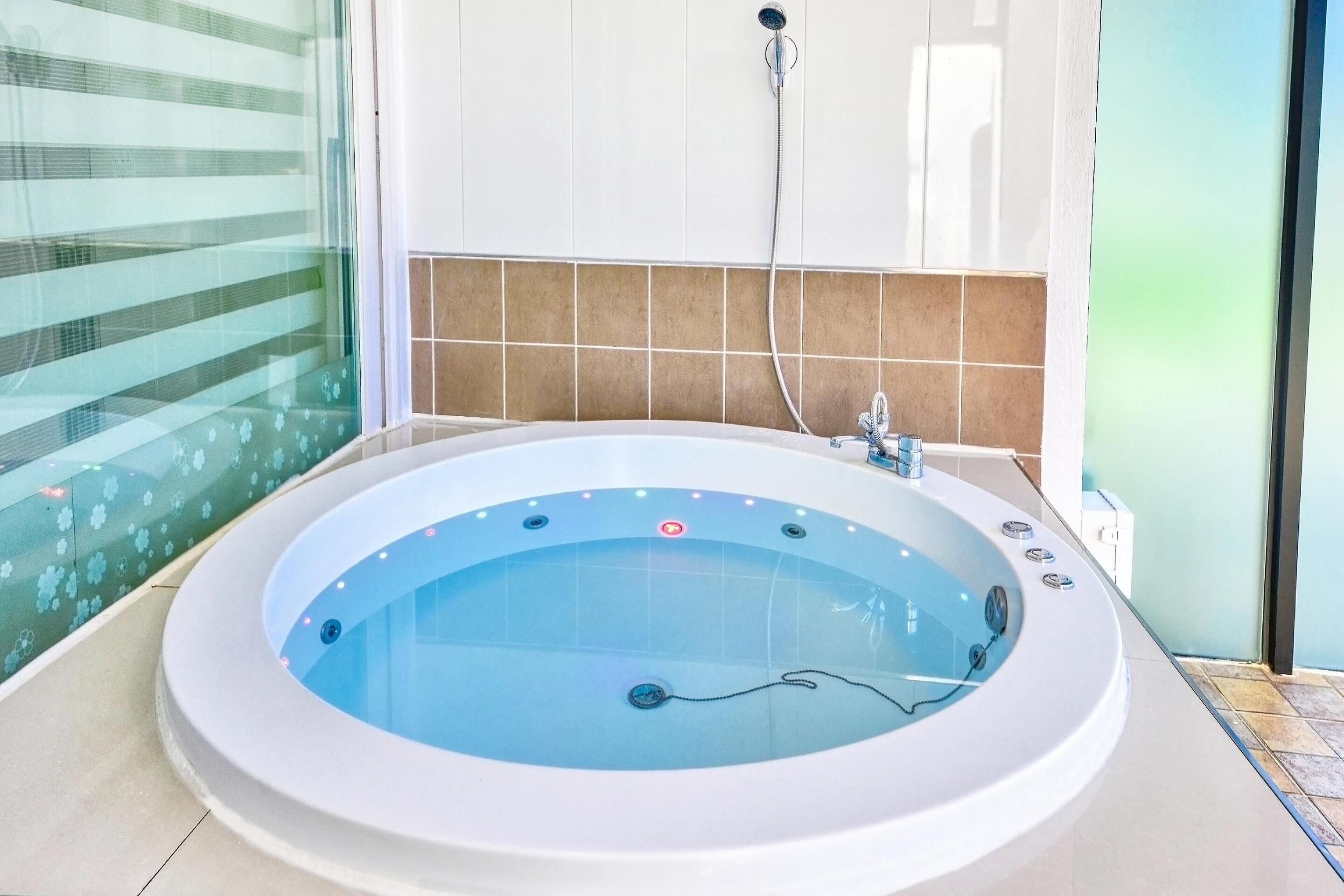 Une salle de bain moderne avec une grande baignoire, une pomme de douche et une paroi de douche en verre.