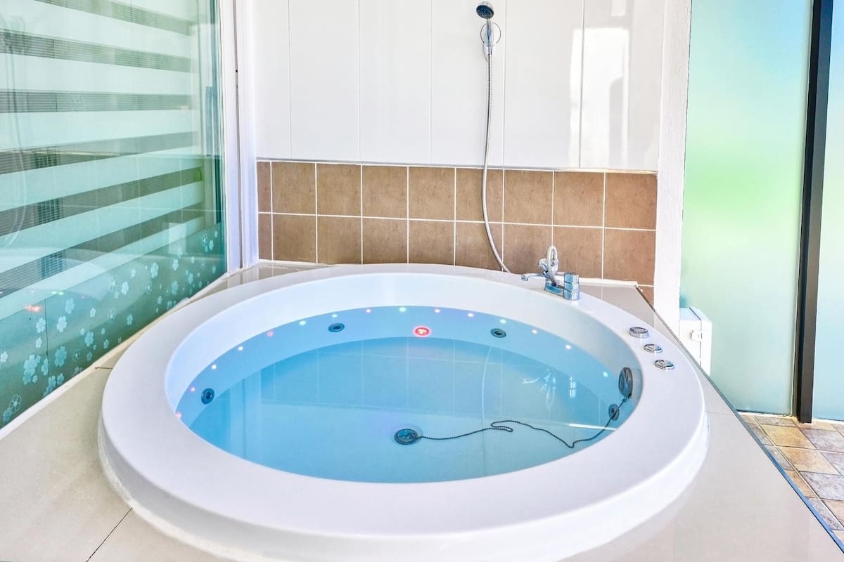 Ein modernes Badezimmer mit einer großen Badewanne, einer Duschbrause und einer Glasdusche.
