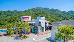A modern building with a 'Colline' sign, surrounded by lush greenery and hills. - Gapyeong Colline Pension (Gapyeong)