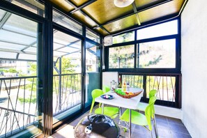 A balcony with a table, chairs, and a grill.