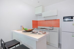 Een kleine keuken met een wit aanrecht, een inbouwoven, een spoelbak en een magnetron.