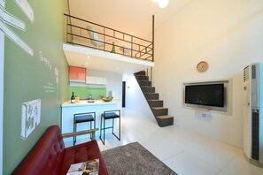 Un espace de vie moderne comprenant une cuisine, un coin repas et un escalier menant à un niveau supérieur.