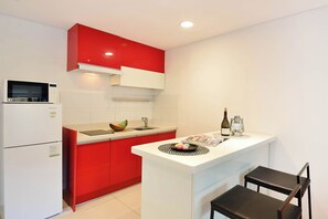 Una cocina compacta con microondas, un lavamanos y un pequeño comedor con una silla.