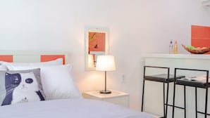 A hotel room with a bed, a nightstand with a lamp, a mirror, and a small table with a basket of fruit. - Gapyeong Colline Pension (Gapyeong)