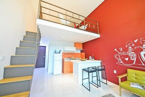 A modern apartment with a staircase, a kitchen, a dining area, and a red accent wall. - Gapyeong Colline Pension (Gapyeong)