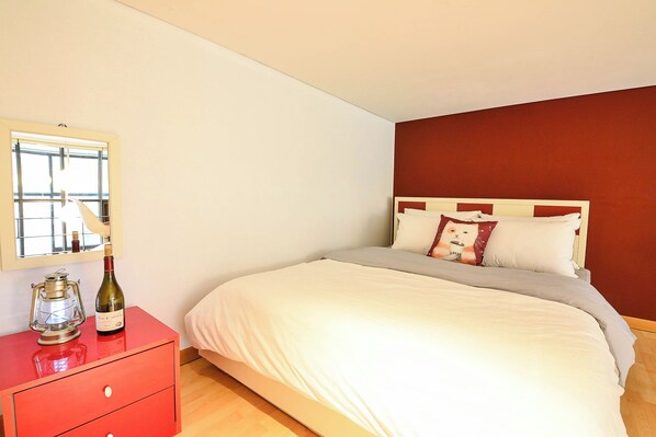 A bedroom with a bed, a dresser, a bottle of wine, and a window. - Gapyeong Colline Pension (Gapyeong)