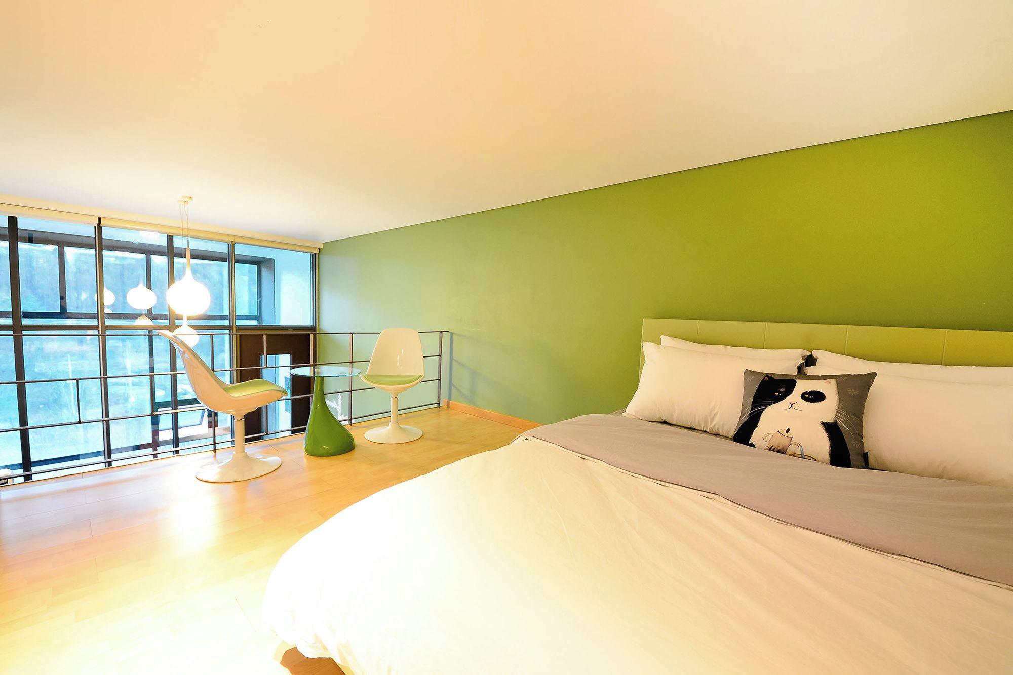 A bedroom with a bed, a green wall, and a window with blinds.