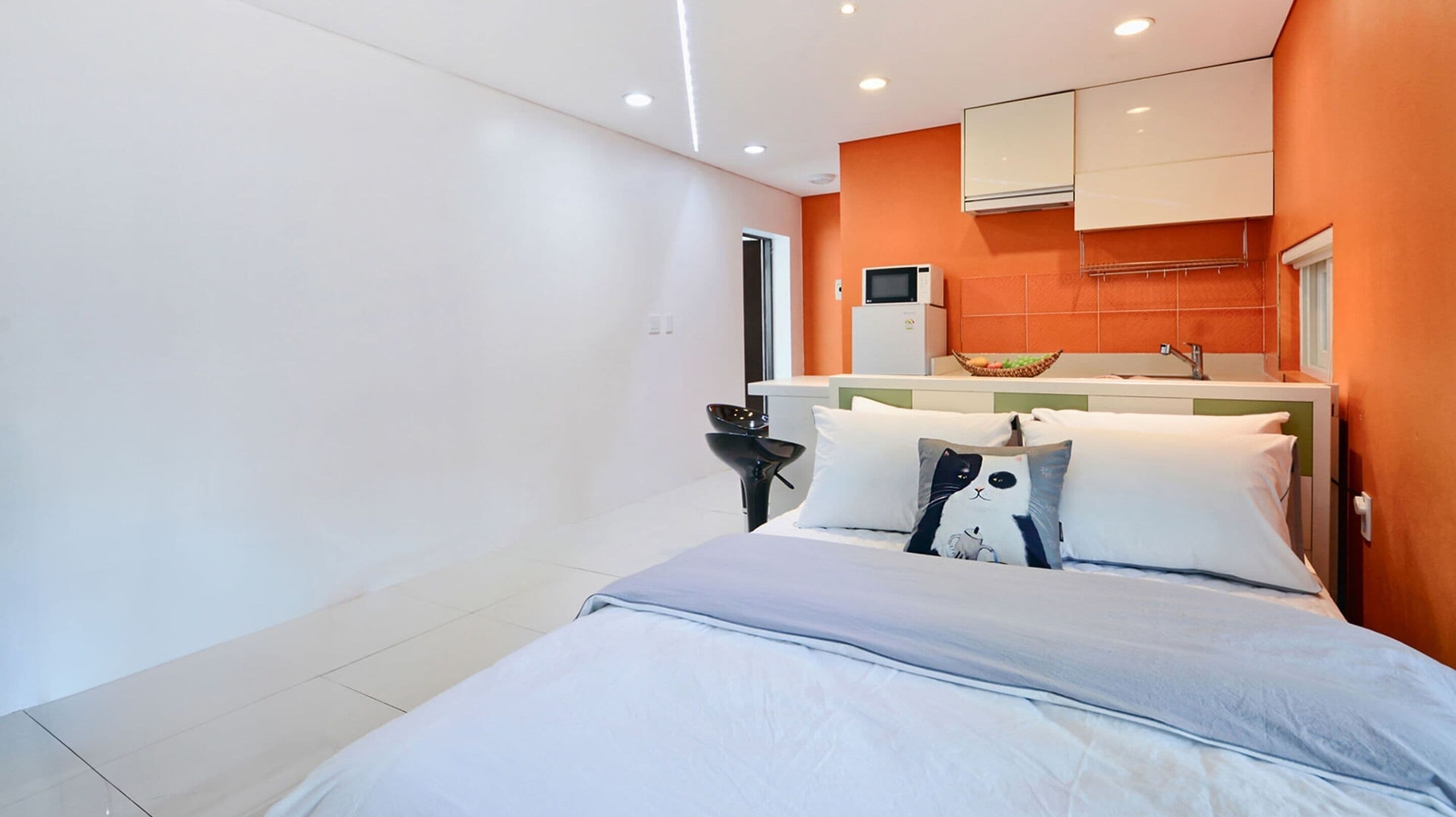 Une chambre d’hôtel moderne équipée d’un lit, d’un petit bureau et d’une kitchenette.
