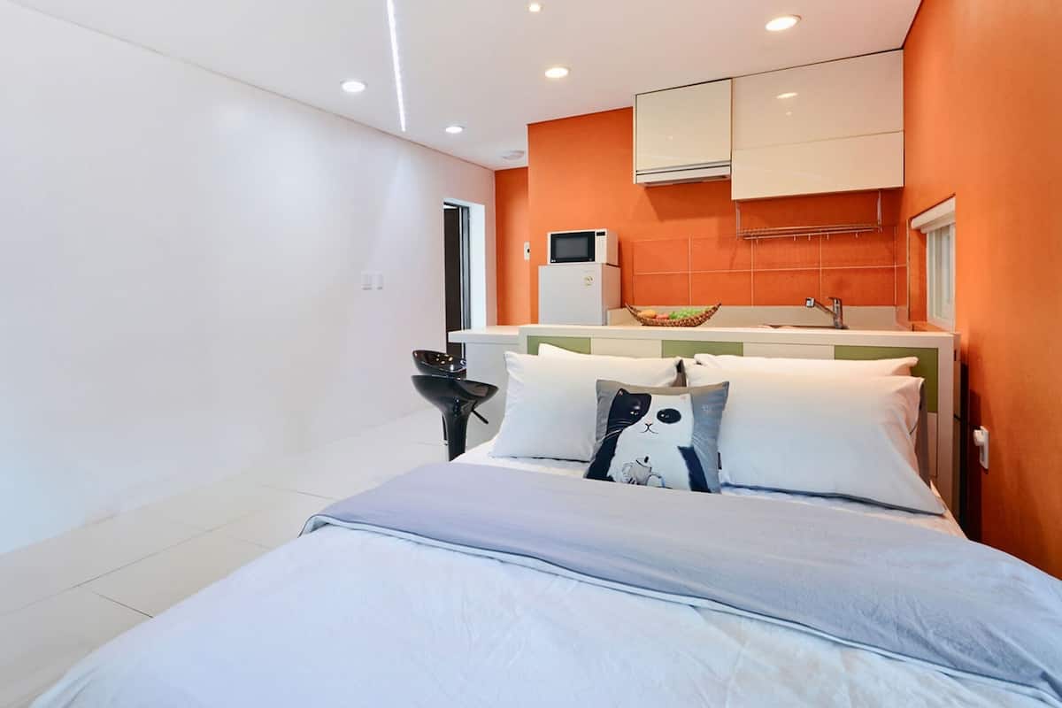Ein modernes Hotelzimmer mit Bett, kleinem Schreibtisch und Küchenzeile.