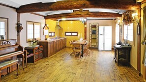 Una cocina amplia con vigas de madera, un piano y un comedor con mesa y sillas.