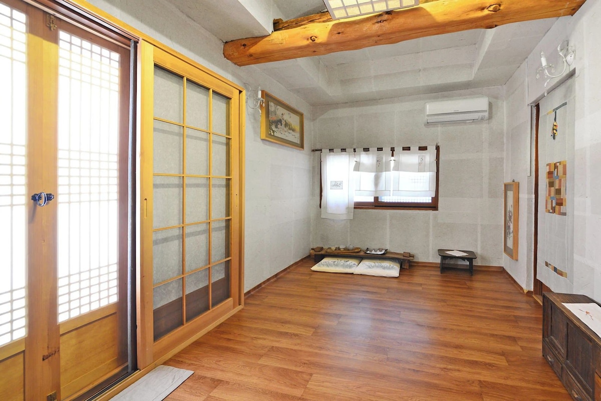 Una habitación japonesa tradicional con suelo de tatami, puertas correderas y viga de madera en el techo.