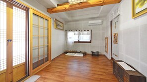 Una habitación japonesa tradicional con suelo de tatami, puertas correderas y viga de madera en el techo.