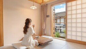 A room with tatami flooring, a low wooden table, and a sliding door leading to an outdoor area with a traditional Japanese-style building. - Gyeongju Hanokstay Hangbokhanzip (Gyeongju)