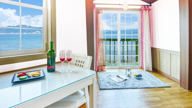 A dining area with a table set for two, a bottle of wine, and a plate of fruit. - Ganghwa Bettel Pension (Incheon)