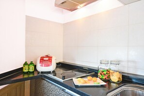 A kitchen with a black countertop, a red toaster, two bottles of beer, a plate with snacks, and two jars of candies. - Ganghwa Bettel Pension (Incheon)