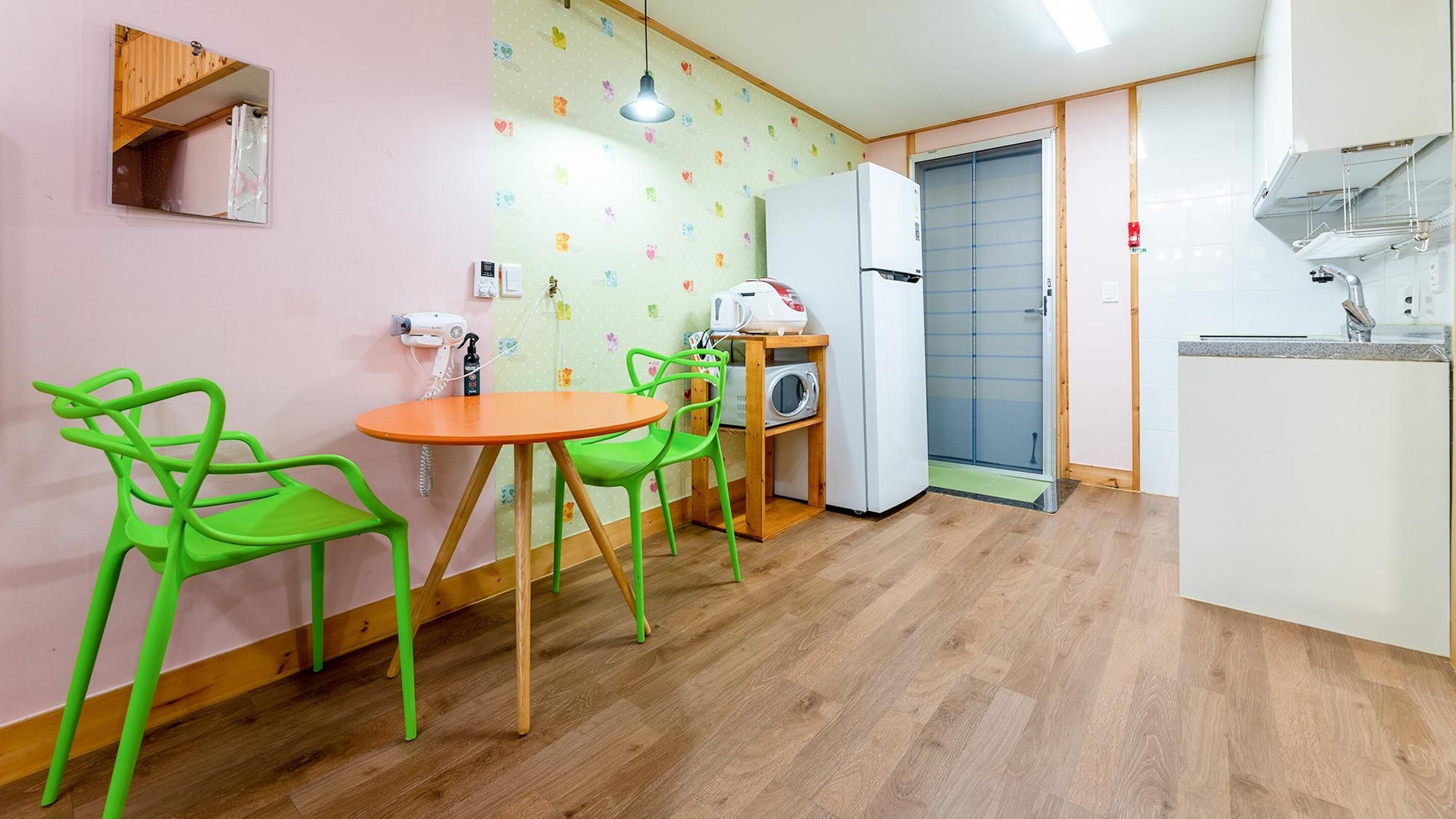 A compact kitchen with a wooden table and chairs, a microwave, and a refrigerator.