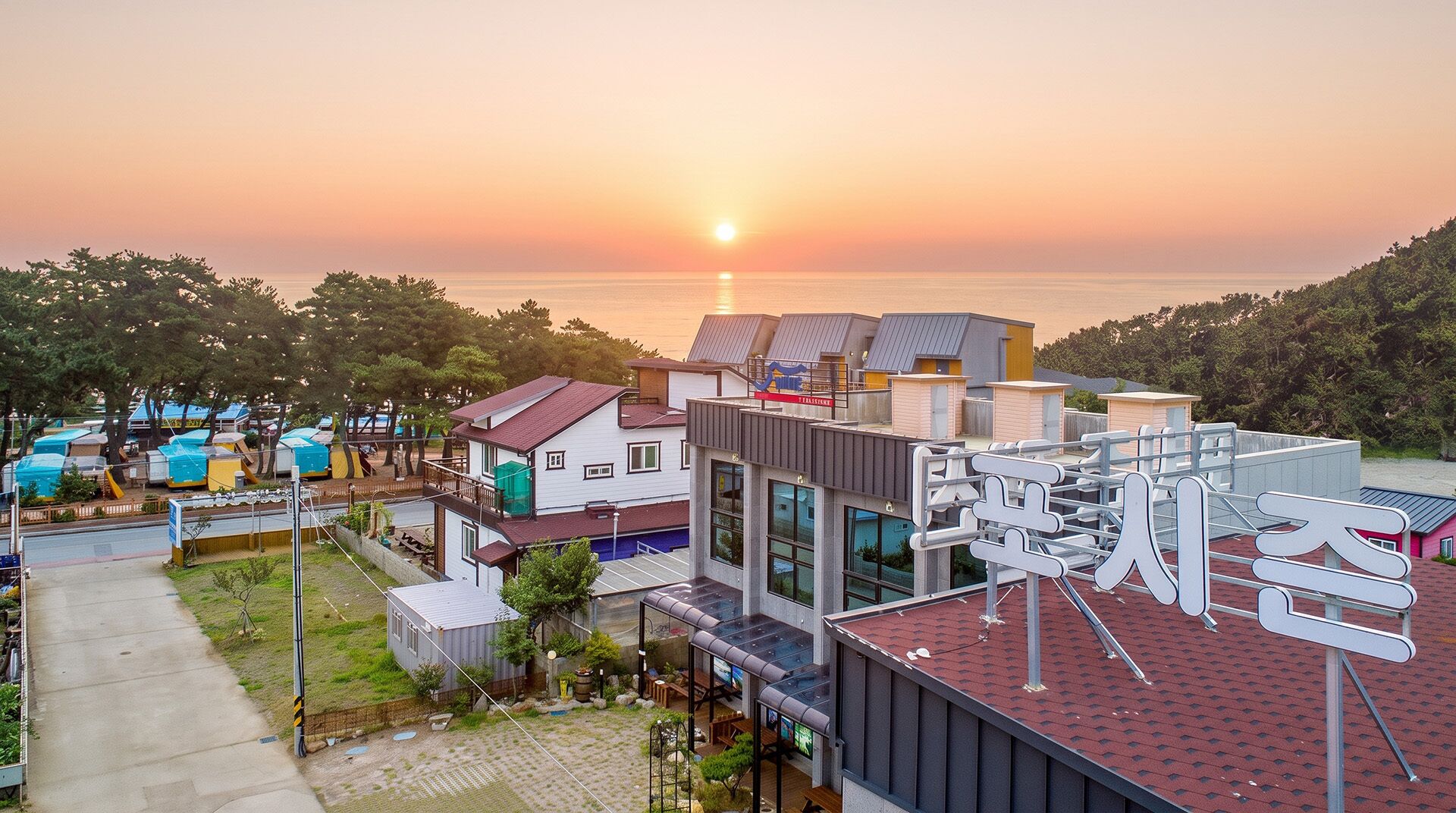 Un hotel costero de arquitectura moderna, con vista al mar y al atardecer.