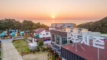 Un hotel costero de arquitectura moderna, con vista al mar y al atardecer.