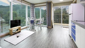 A modern kitchen with a large window, a dining area with chairs, and a flat-screen TV. - Hongcheon When You Are There Pension (Hongcheon)