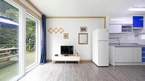 A modern kitchen with white cabinets, a built-in microwave, and a large window overlooking a deck. - Hongcheon When You Are There Pension (Hongcheon)