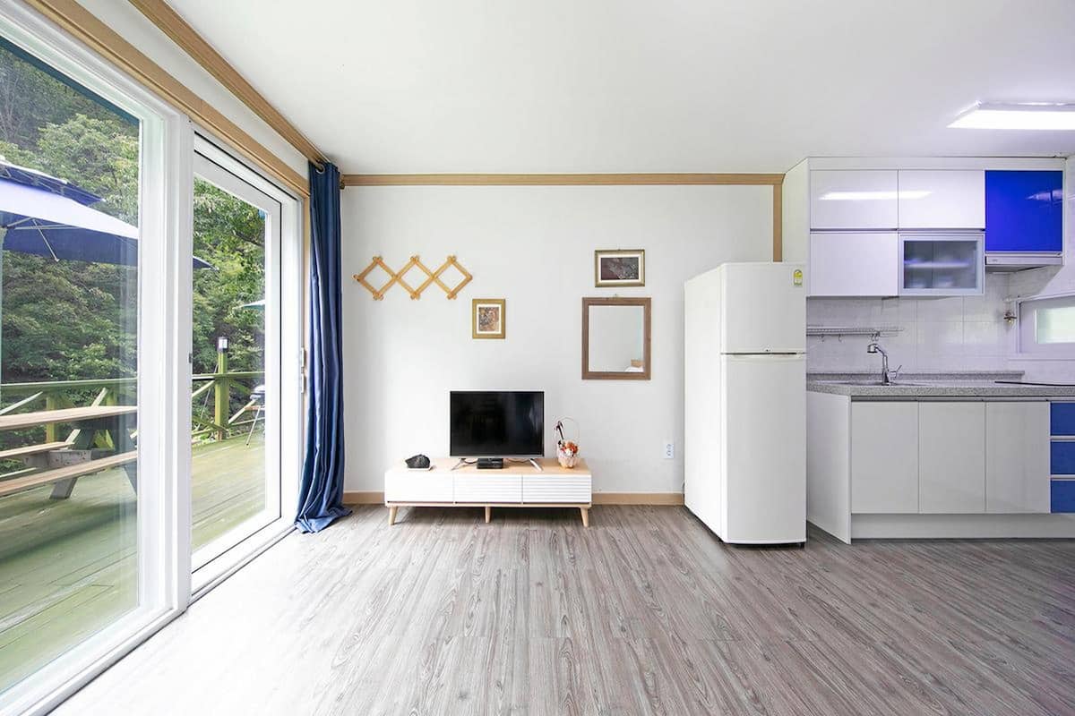 A modern kitchen with white cabinets, a built-in microwave, and a large window overlooking a deck.
