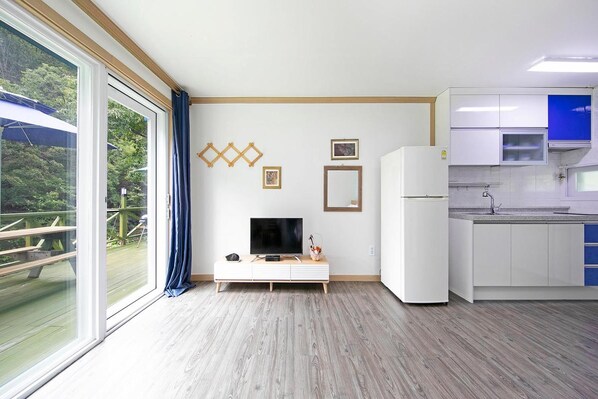 Une cuisine moderne avec des armoires blanches, un four à micro-ondes encastré et une grande fenêtre donnant sur une terrasse.