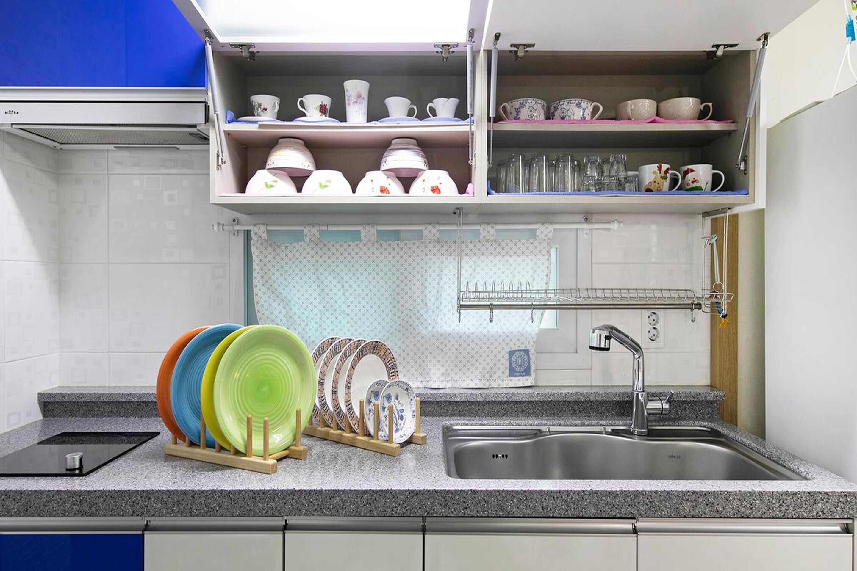 A kitchen with a granite countertop, a stainless steel sink, and a dish rack.