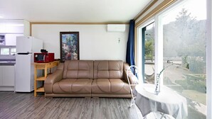 A compact living space with a sofa, a small table, a microwave, and a refrigerator. - Hongcheon When You Are There Pension (Hongcheon)