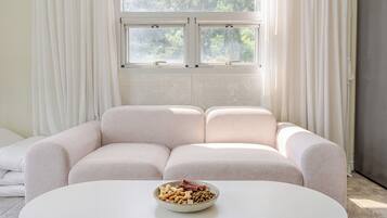 Una sala moderna con un sofá, una mesa de centro y un ventanal con cortinas.