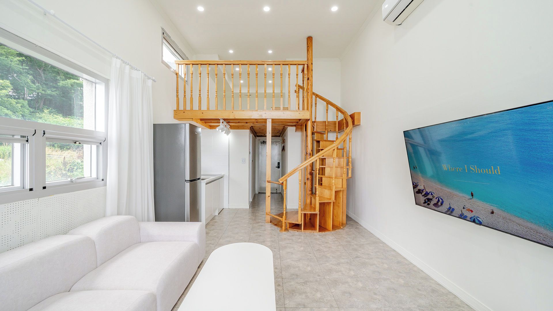 Um interior moderno com escada, um sofá branco e uma janela ampla.