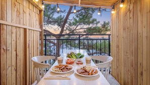 Eine Holzterrasse mit gedecktem Tisch, umgeben von Kiefern.