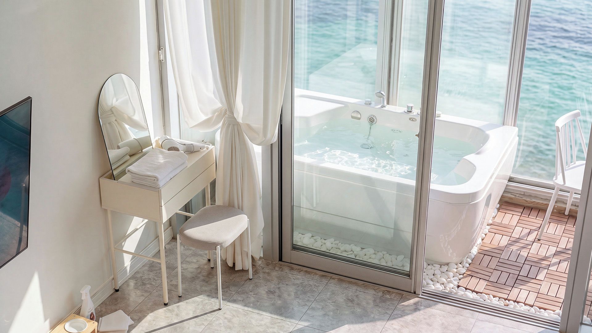 Un baño moderno con un jacuzzi de vidrio, un tocador con espejo y vistas al mar.