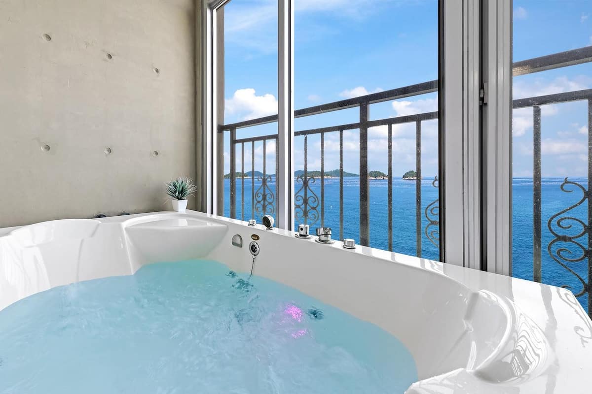 Una bañera grande con vista al mar a través de la barandilla de un balcón.