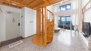 Ein geräumiges Zimmer mit einer Holzspirale, einem großen Fenster mit Blick und einem modernen Interieur.