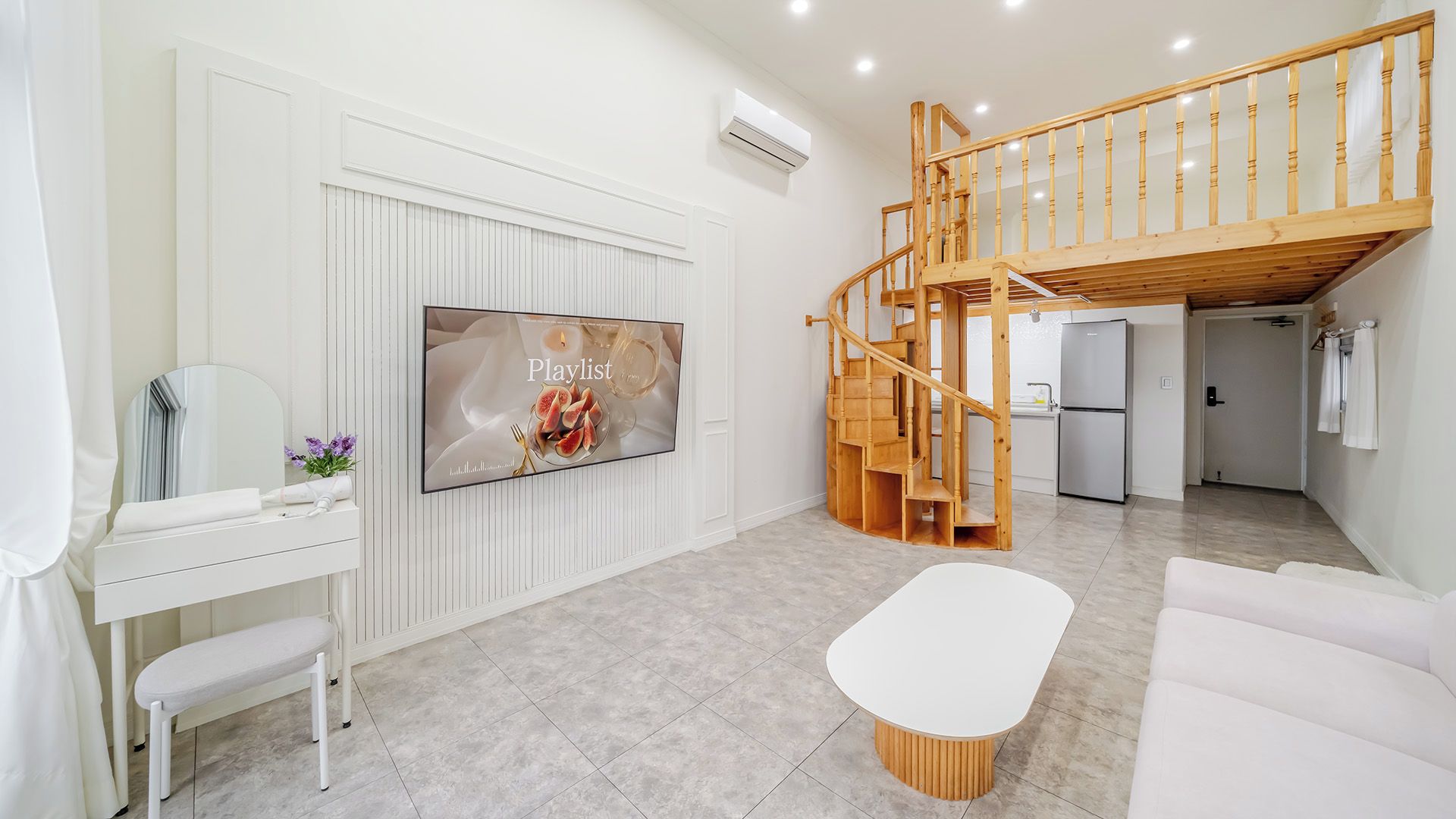 Una sala de estar moderna con un televisor de pantalla plana, una escalera de madera y un sofá blanco.