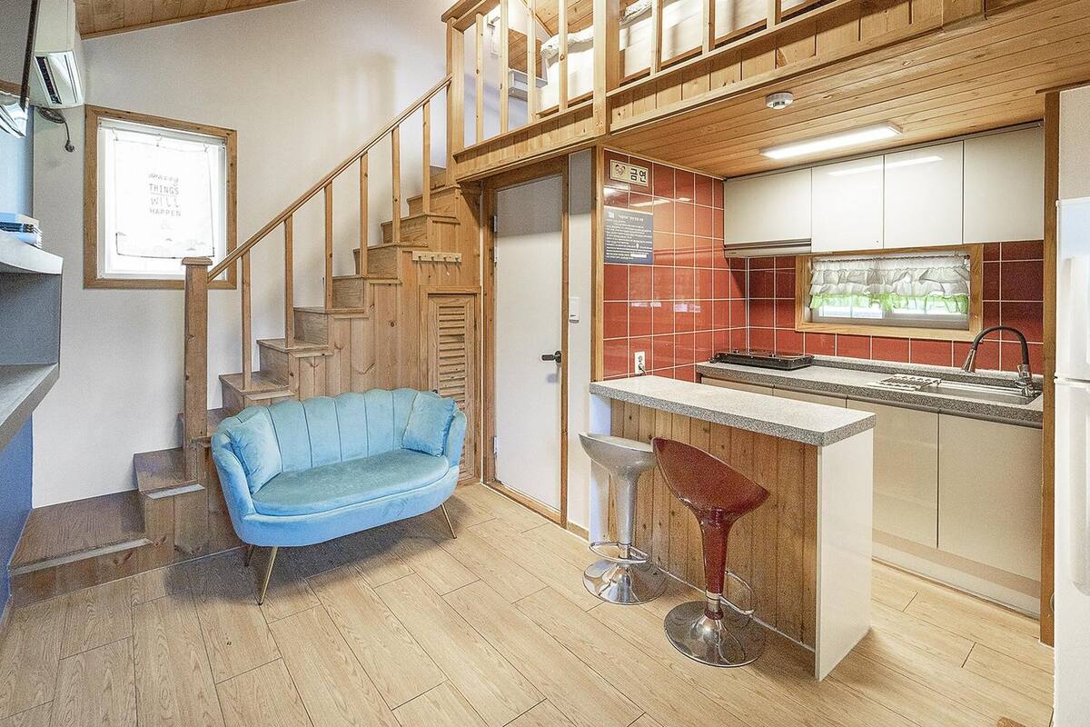 Una cocina funcional con armarios de madera, estufa integrada y una barra con taburetes.