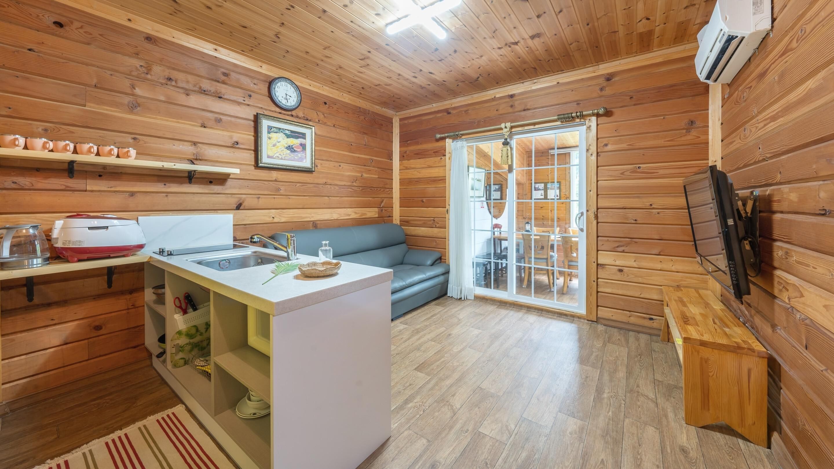 A cozy cabin interior with a kitchenette, a sofa, and a television.