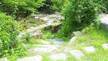 A natural outdoor setting with a clear stream, rocks, and a wooden bench.